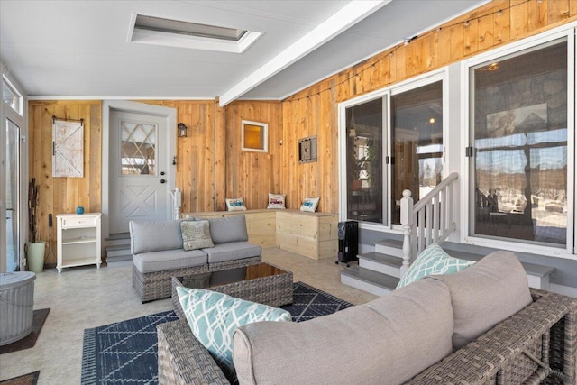 living area featuring beam ceiling and wooden walls