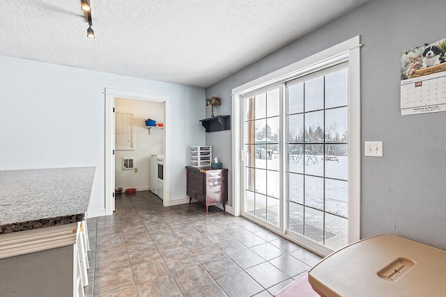 interior space with light tile patterned flooring, washer / dryer, track lighting, and a textured ceiling