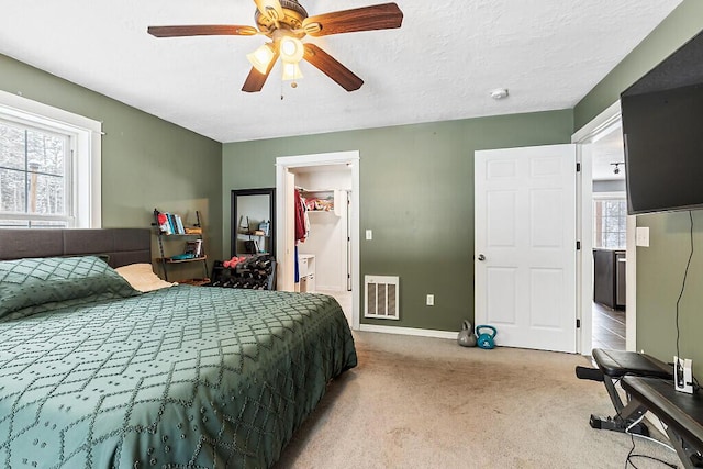 bedroom featuring ceiling fan, light carpet, and a textured ceiling