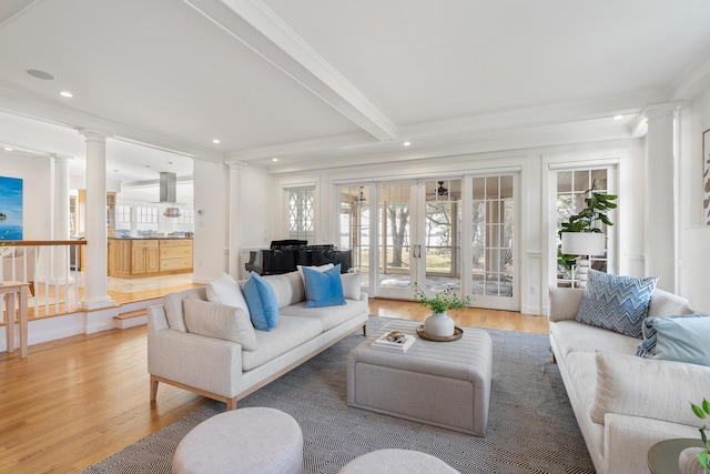 living area with light wood finished floors, ornamental molding, and ornate columns