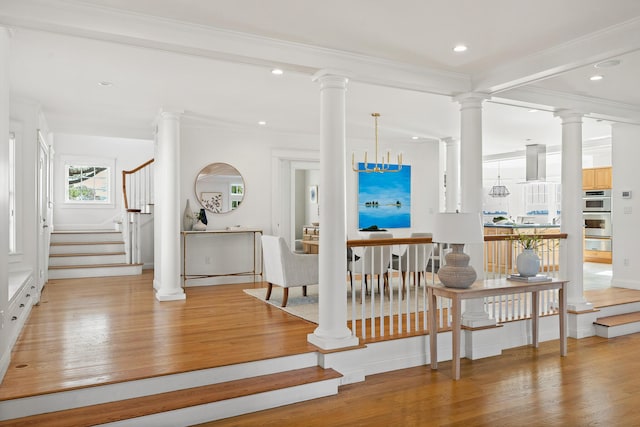 interior space featuring stairs, light wood-style floors, ornate columns, ornamental molding, and recessed lighting