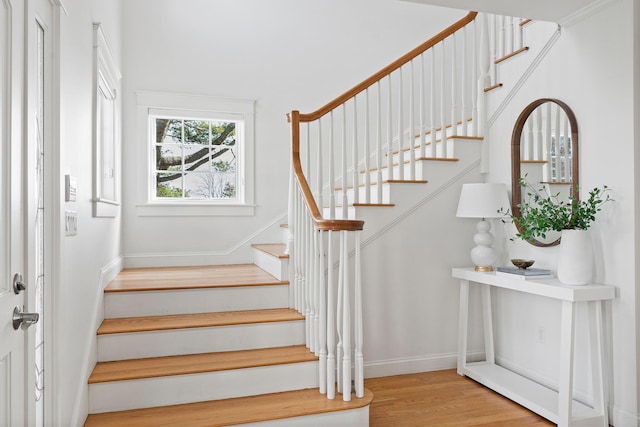 staircase featuring wood finished floors and baseboards