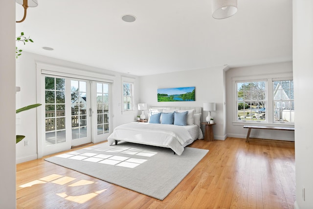 bedroom featuring multiple windows, wood finished floors, access to outside, and french doors