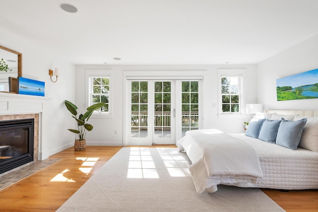 bedroom with a fireplace, wood finished floors, access to outside, and multiple windows