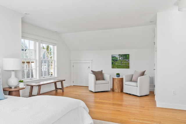 bedroom featuring light wood-style floors, lofted ceiling, and baseboards