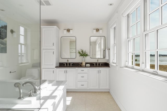 full bath with tile patterned flooring, a sink, double vanity, and toilet