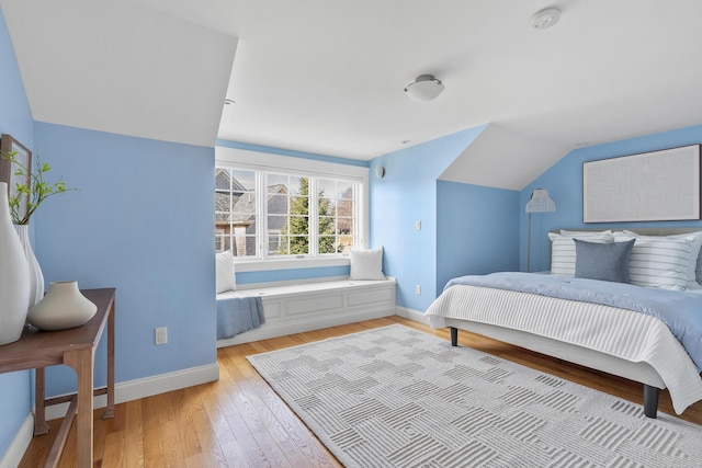 bedroom with baseboards, lofted ceiling, and wood finished floors