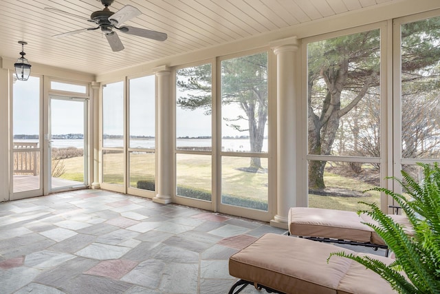 sunroom with stone tile floors and a water view