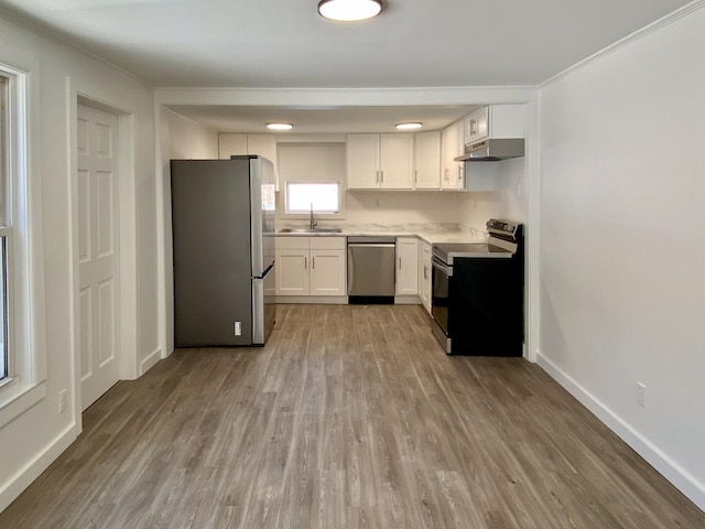 kitchen with sink, white cabinetry, light wood-type flooring, ornamental molding, and stainless steel appliances