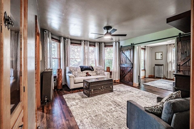 living room featuring a barn door, dark wood-type flooring, and ceiling fan