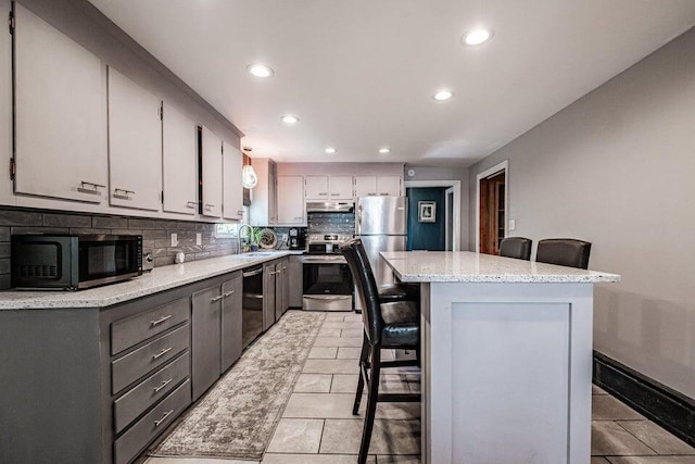 kitchen with appliances with stainless steel finishes, sink, a kitchen bar, and decorative backsplash