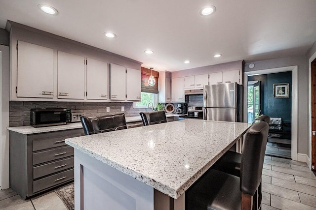 kitchen featuring pendant lighting, decorative backsplash, a breakfast bar, and appliances with stainless steel finishes