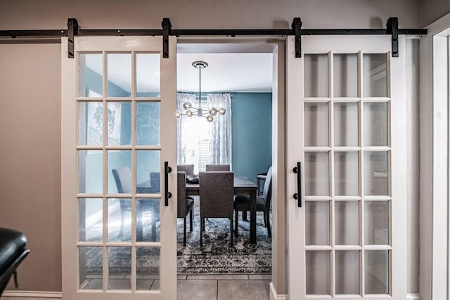 interior space featuring an inviting chandelier, a barn door, and tile patterned flooring