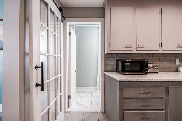 kitchen featuring light stone counters, a barn door, and decorative backsplash