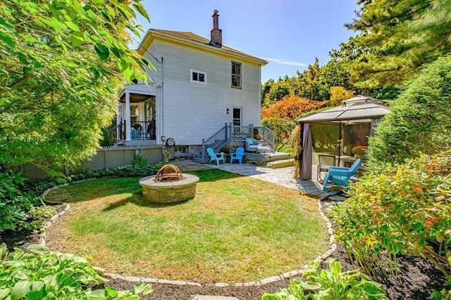 back of property featuring a yard, a fire pit, a patio area, and a gazebo