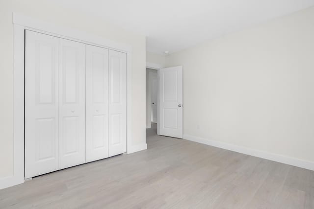 unfurnished bedroom featuring light wood-type flooring and a closet