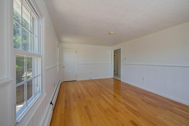 3 Sea Breeze Ave, Biddeford, ME 04005 - empty room featuring light wood-type flooring, a textured ceiling, and a wainscoted wall