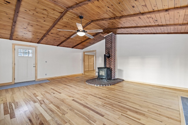 unfurnished living room featuring vaulted ceiling with beams, a wood stove, wooden ceiling, ceiling fan, and light hardwood / wood-style floors