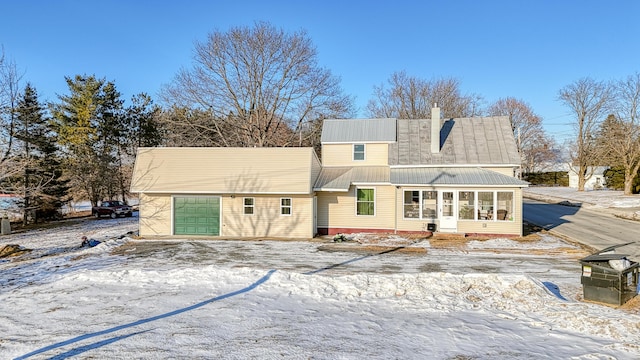 snow covered back of property with a garage