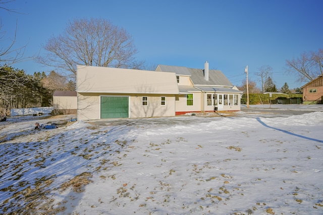 snow covered rear of property with a sunroom