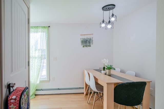 dining room featuring an inviting chandelier, a baseboard heating unit, and light hardwood / wood-style floors