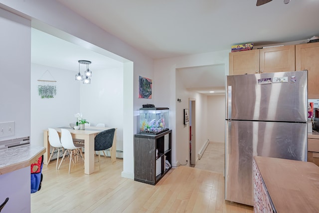 kitchen featuring stainless steel fridge, baseboard heating, hanging light fixtures, light brown cabinetry, and light wood-type flooring