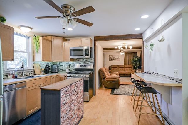 kitchen with sink, light brown cabinets, appliances with stainless steel finishes, light hardwood / wood-style floors, and decorative backsplash