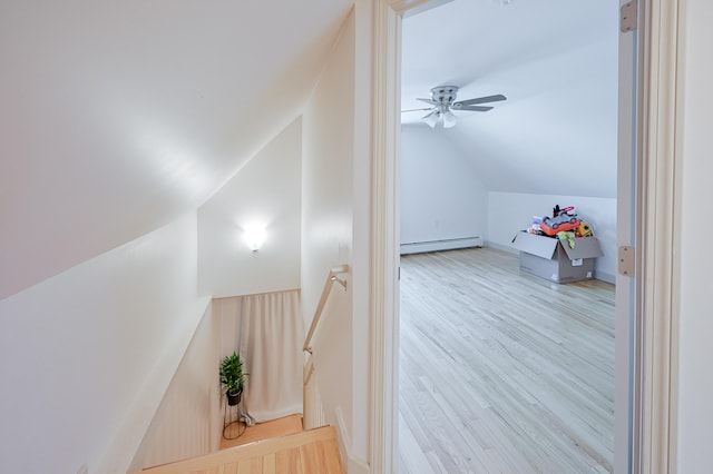 interior space with ceiling fan, lofted ceiling, baseboard heating, and light hardwood / wood-style floors