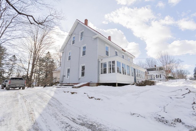 view of snowy exterior with a sunroom