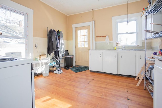 kitchen with a healthy amount of sunlight, pendant lighting, white cabinets, and light wood-type flooring