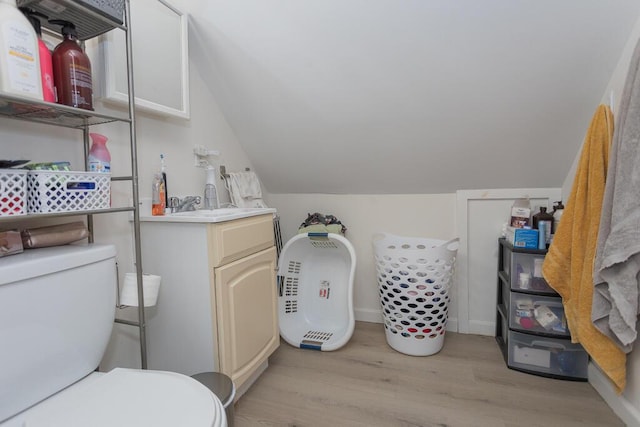 bathroom featuring lofted ceiling, vanity, wood-type flooring, and toilet