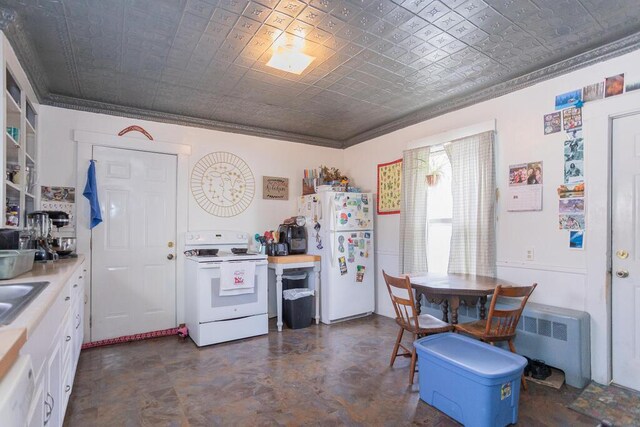 kitchen with sink, ornamental molding, radiator, white appliances, and white cabinets