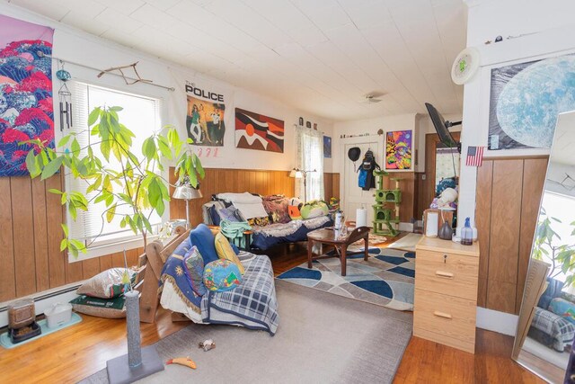 living area featuring hardwood / wood-style floors, wooden walls, and baseboard heating