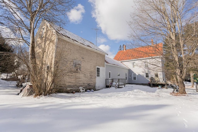 snow covered back of property featuring a wooden deck