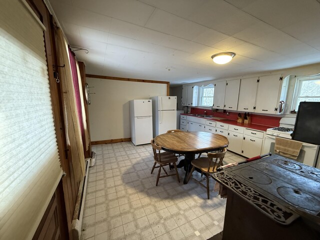 kitchen featuring sink, white appliances, white cabinets, and baseboard heating