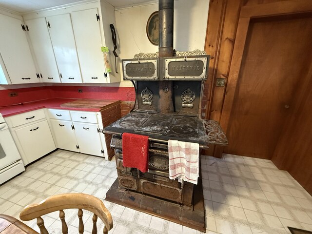 kitchen with white cabinetry, a wood stove, and stove