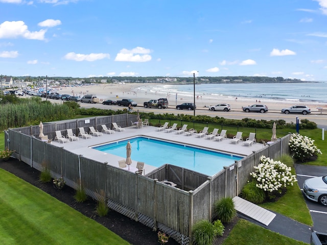 community pool featuring a water view, fence, a lawn, and a patio area