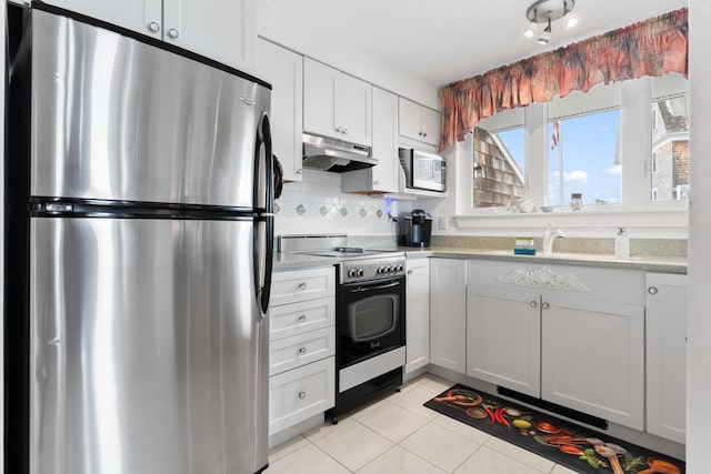 kitchen with under cabinet range hood, appliances with stainless steel finishes, light tile patterned flooring, and light countertops