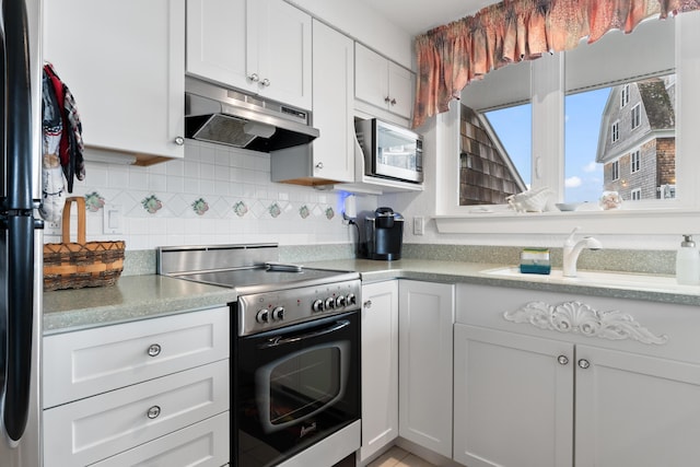 kitchen featuring under cabinet range hood, stainless steel microwave, backsplash, electric range oven, and white cabinetry