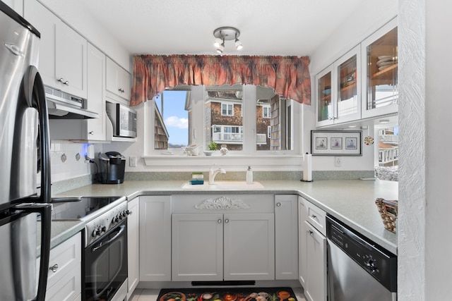 kitchen featuring under cabinet range hood, light countertops, appliances with stainless steel finishes, and a sink