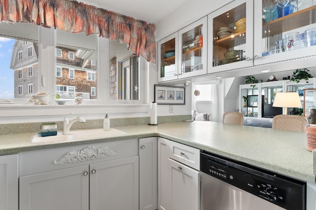 kitchen with glass insert cabinets, dishwasher, light countertops, white cabinetry, and a sink