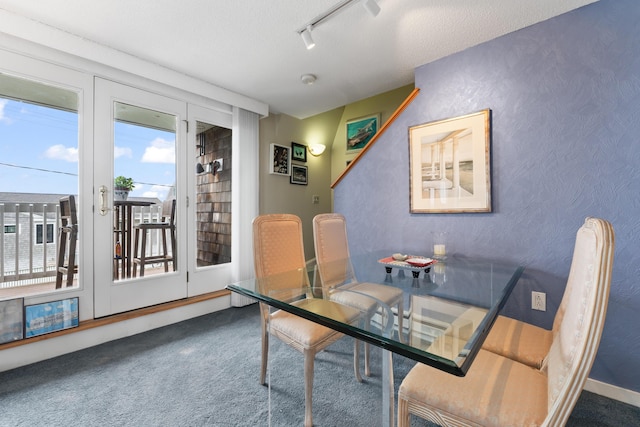 dining area with rail lighting, a textured wall, carpet floors, and a textured ceiling