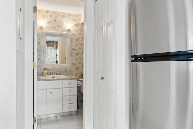 bathroom with vanity, wallpapered walls, tile patterned flooring, a textured ceiling, and toilet