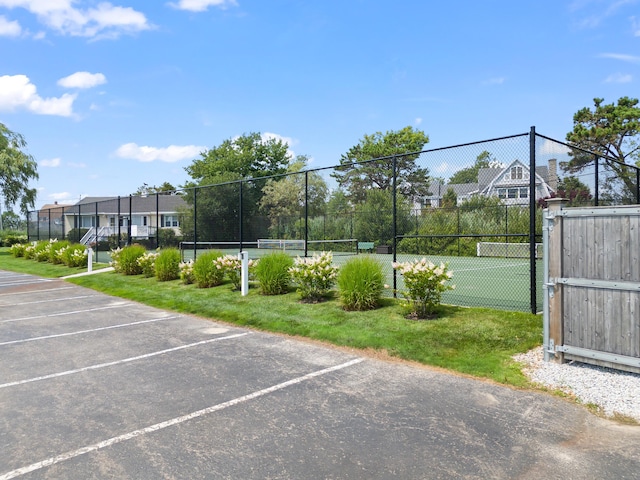 uncovered parking lot featuring a tennis court and fence