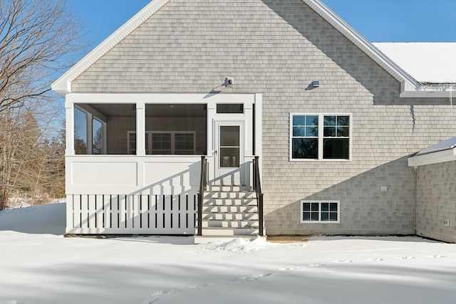 snow covered house featuring a sunroom