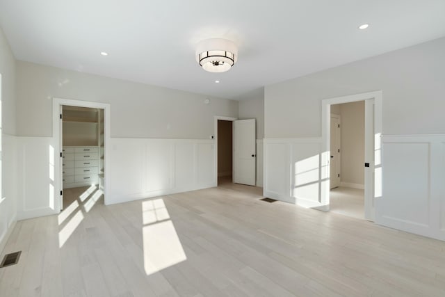 unfurnished bedroom featuring a closet, a walk in closet, and light hardwood / wood-style flooring