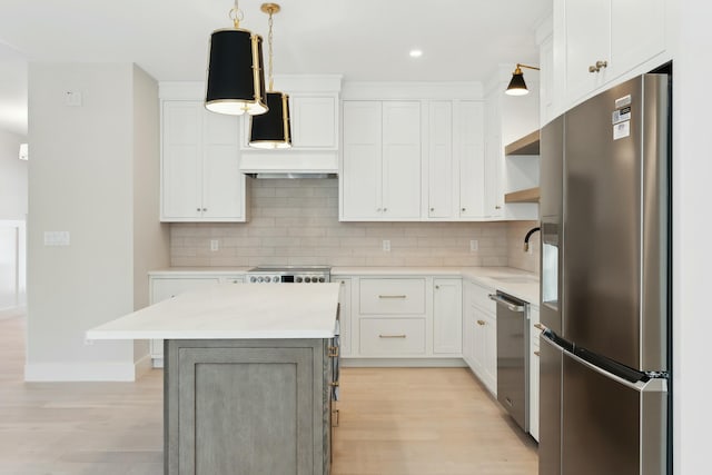 kitchen with pendant lighting, appliances with stainless steel finishes, a center island, and white cabinets