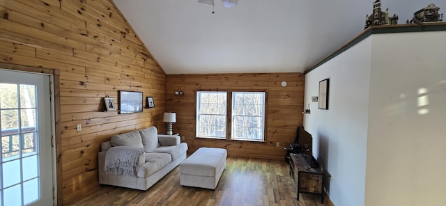 living room with hardwood / wood-style flooring, vaulted ceiling, and wood walls