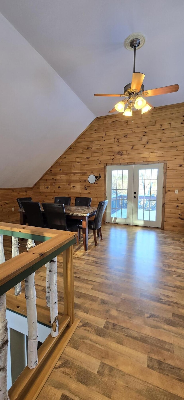 additional living space with hardwood / wood-style flooring, ceiling fan, lofted ceiling, and wooden walls