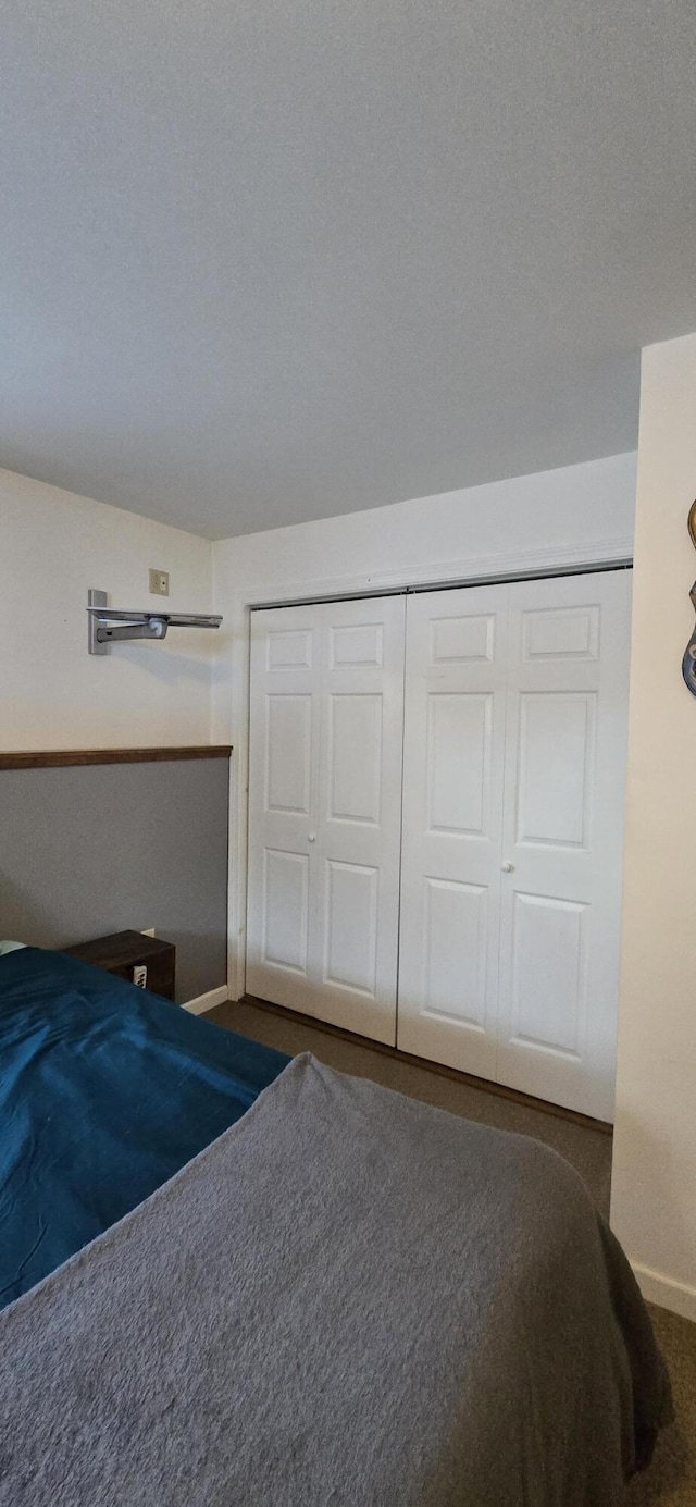 unfurnished bedroom with a textured ceiling, dark carpet, and a closet